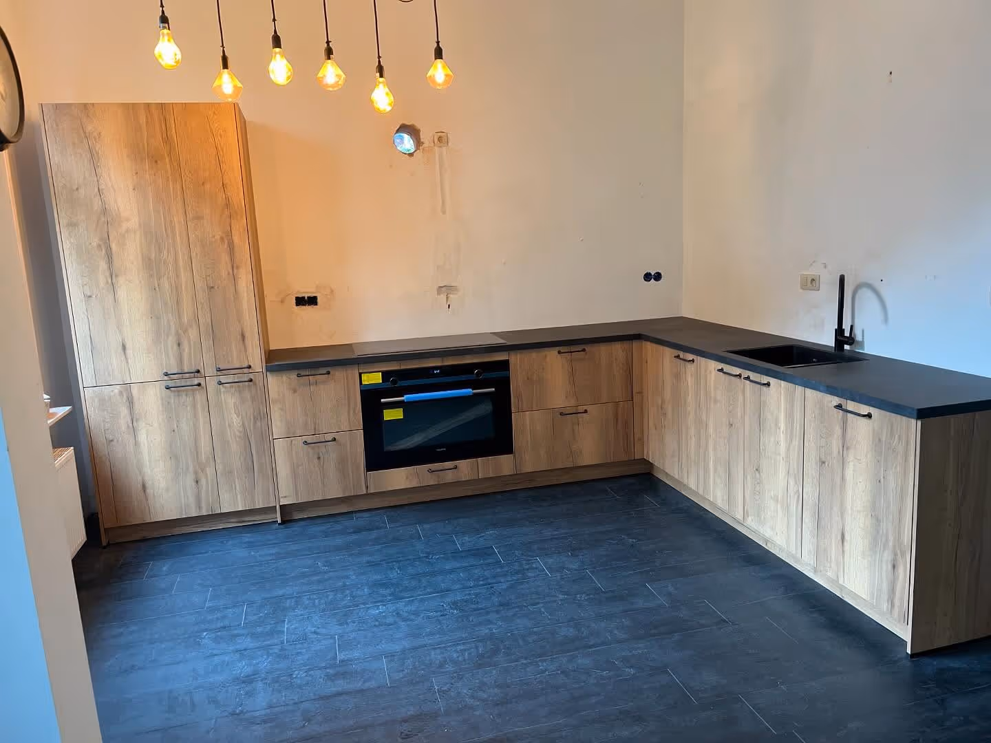  A brightly lit corner of a room features a modern white armchair with light wood accents, a small white coffee table with a plant, and a clear vase with white branches next to a sunlit window.