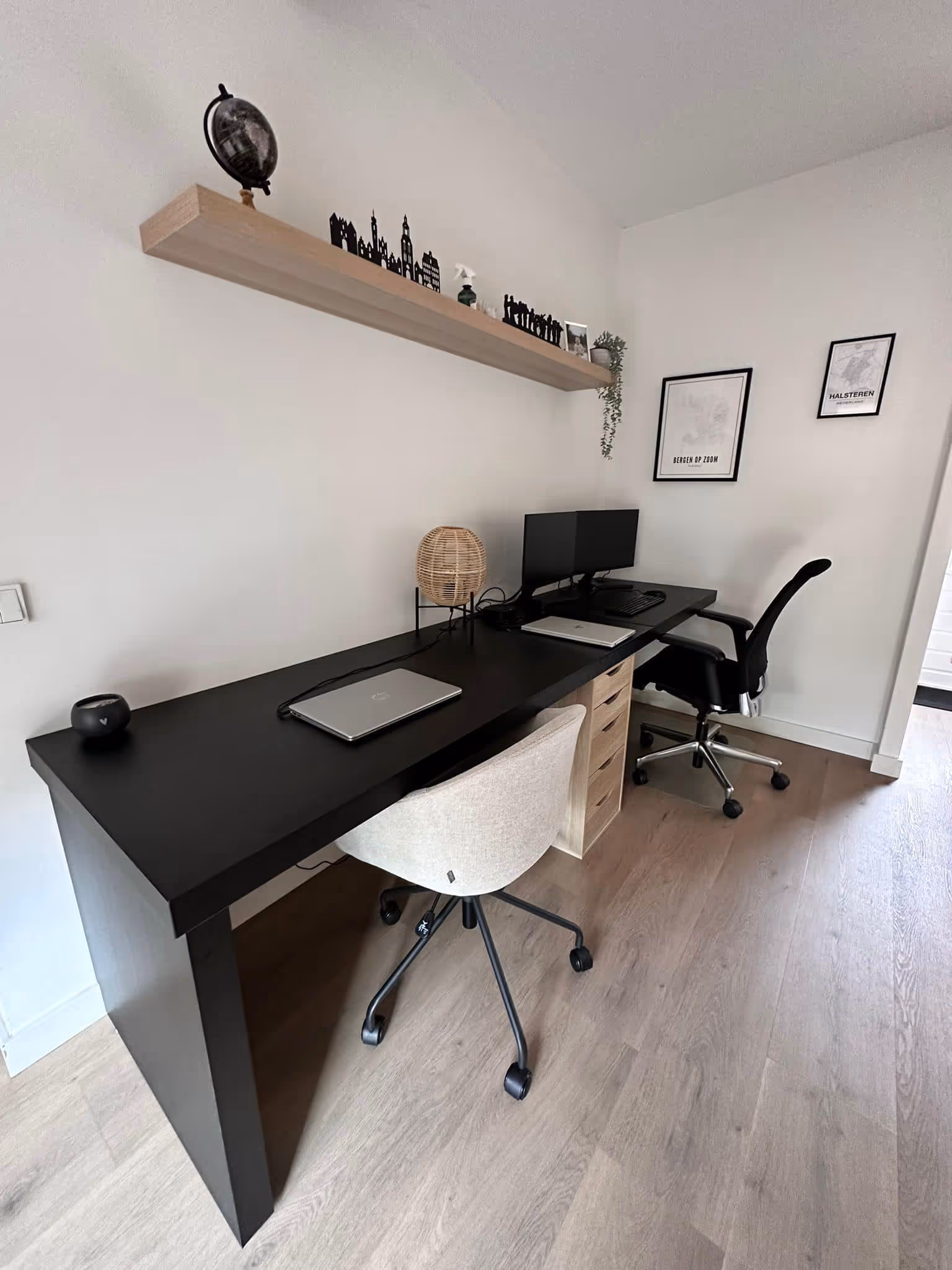 A modern bedroom with a white bed, wooden headboard, black lamp on a side table, and high windows